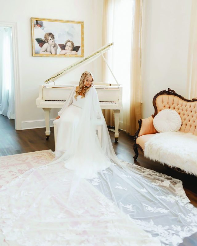 A bride at the white grand piano, veil spread across the floor