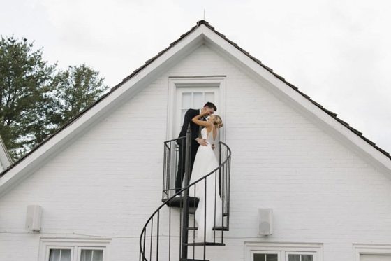 A couple on the spiral stair against the white clapboard