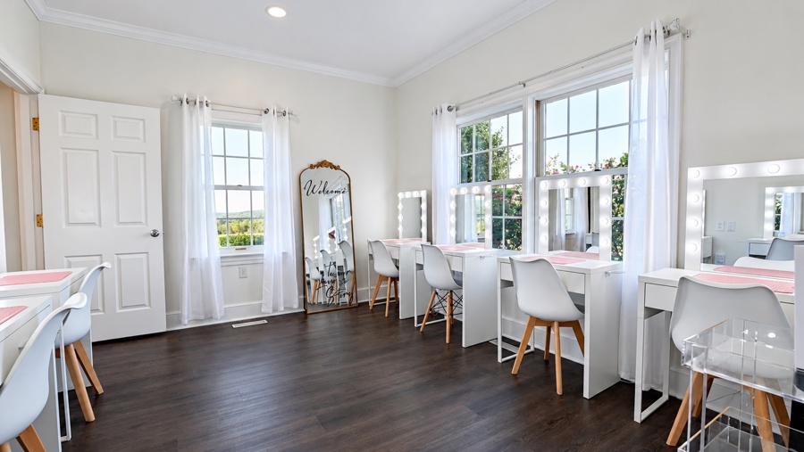 The bridal suite: a row of lit vanity mirrors and chairs beside tall windows