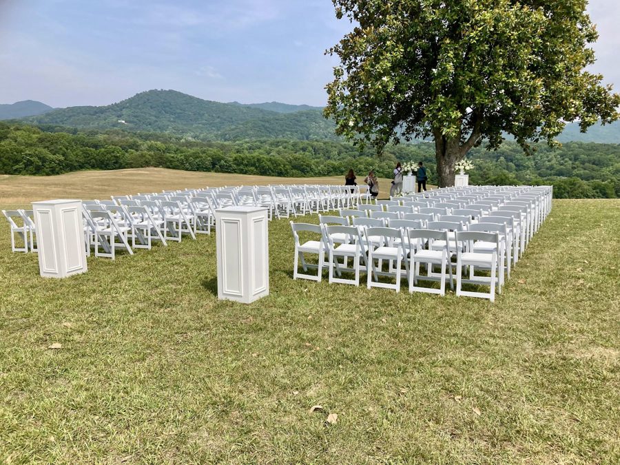 Ceremony chairs set on the crest beneath the tree, ridgelines beyond